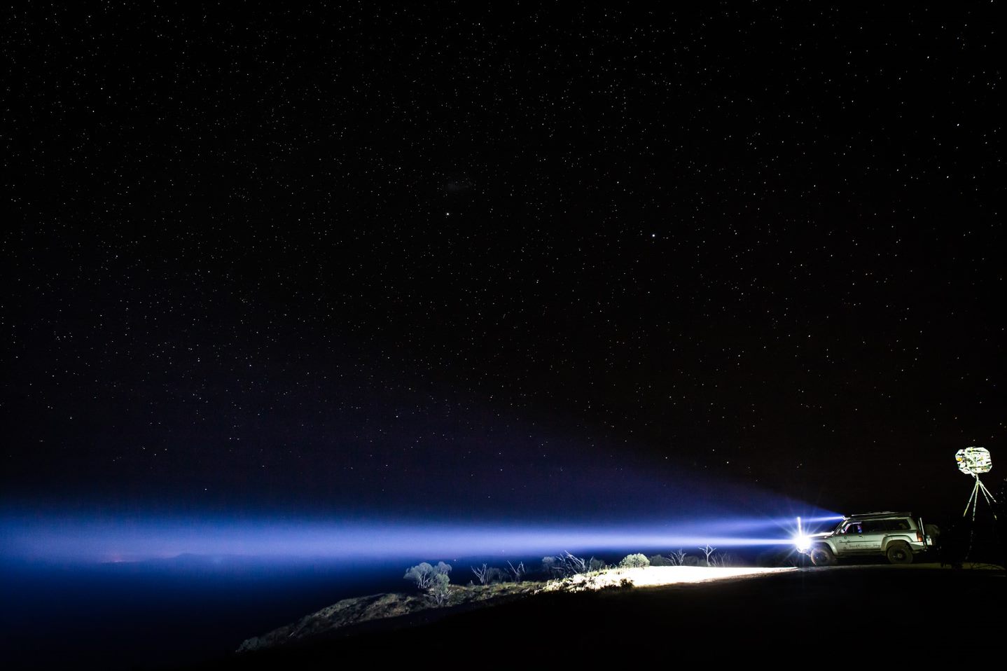 Four-wheel drive casting a long beam of light under a night sky